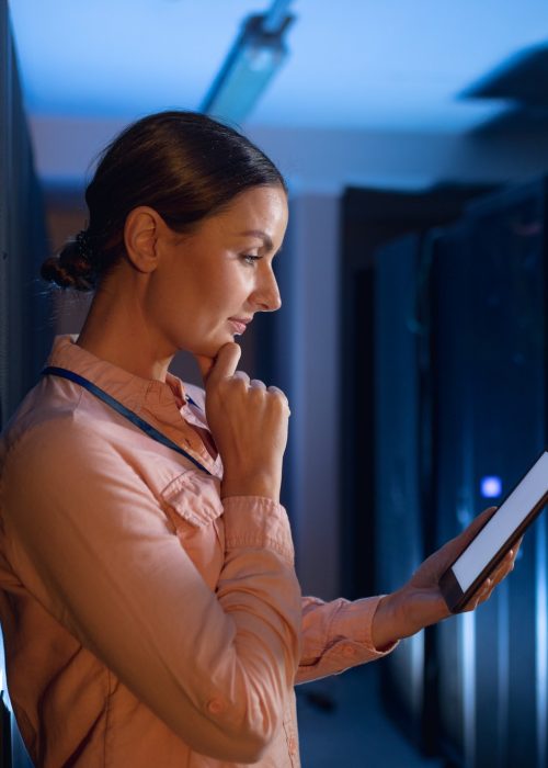 Thoughtful caucasian female engineer using digital tablet in computer server room
